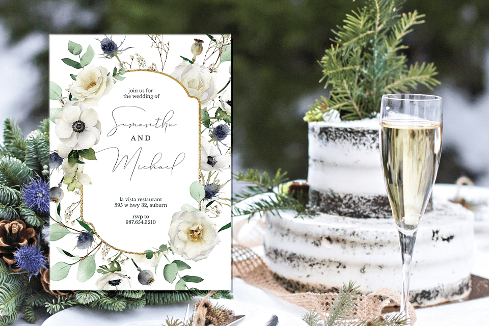 A winter wedding invitation framed by white flowers and green leaves, with text inside a golden border. The background features an outdoor wedding setting, including a decorated table with a cake, champagne glasses, and a bouquet of winter flowers.