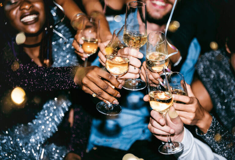 Festive New Year Celebration: Joyful individuals adorned in colorful attire raise their champagne glasses in cheerful toast, enveloped in an atmosphere of happiness and merriment as they ring in the new year.