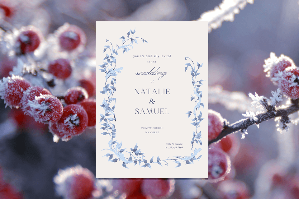 An elegant winter wedding invitation featuring a border of intricately illustrated frozen flowers in light blue, lending a touch of serene beauty. The background presents a view of snow-covered tree branches, adding a sense of tranquil winter wonder to the design.