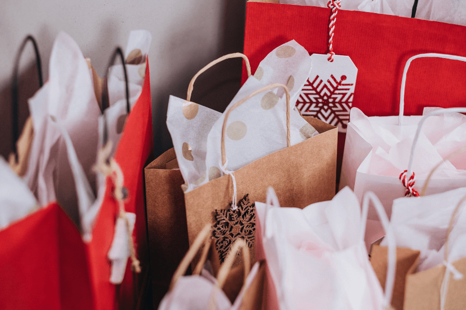 An assortment of festive gift bags and wrapping materials, including intricately patterned paper and tags adorned with delicate snowflake shapes.