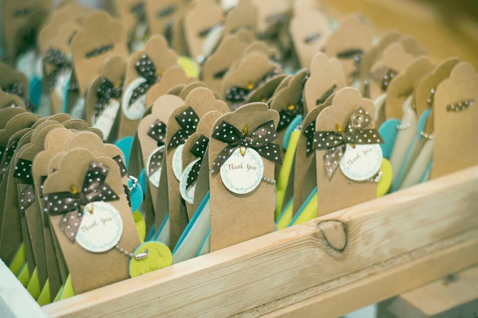 A row of elegantly designed small wedding favor paper bags, each adorned with a chic black bow featuring white polka dots, creating a stylish and celebratory appearance.