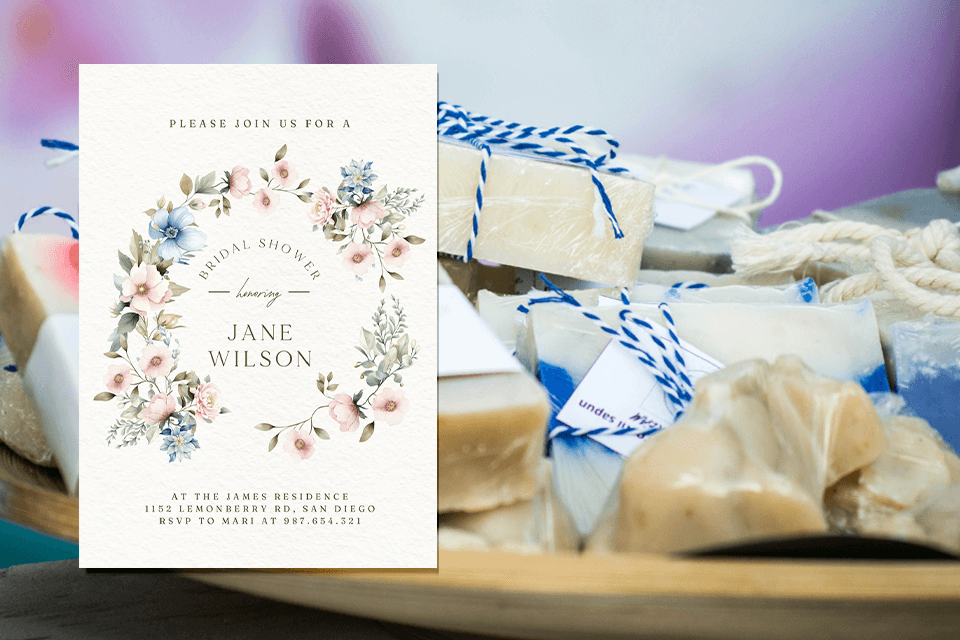 Bridal Shower Invitation featuring a soft, pastel floral wreath painted in watercolors. The invitation is elegantly placed atop a background adorned with party favors like delicate soaps, setting the tone for a charming and delightful celebration. Image in an article about Bridal Shower games