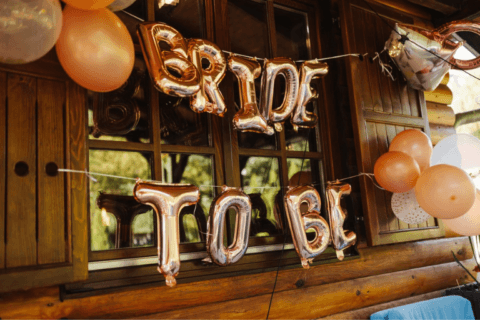 ‘Bride to Be’ gleams in golden balloons, enhancing the outdoor ambiance of a bridal shower party. Surrounding it, melon-colored balloons add a pop of vibrant color, setting the stage for a joyous celebration under the open sky.