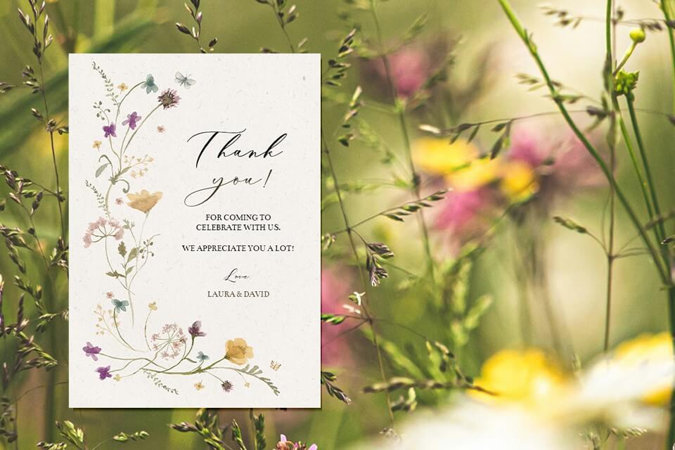 Graceful post-wedding thank you card featuring a minimalist, delicate flower illustration against a serene meadow backdrop blooming with vibrant hues.