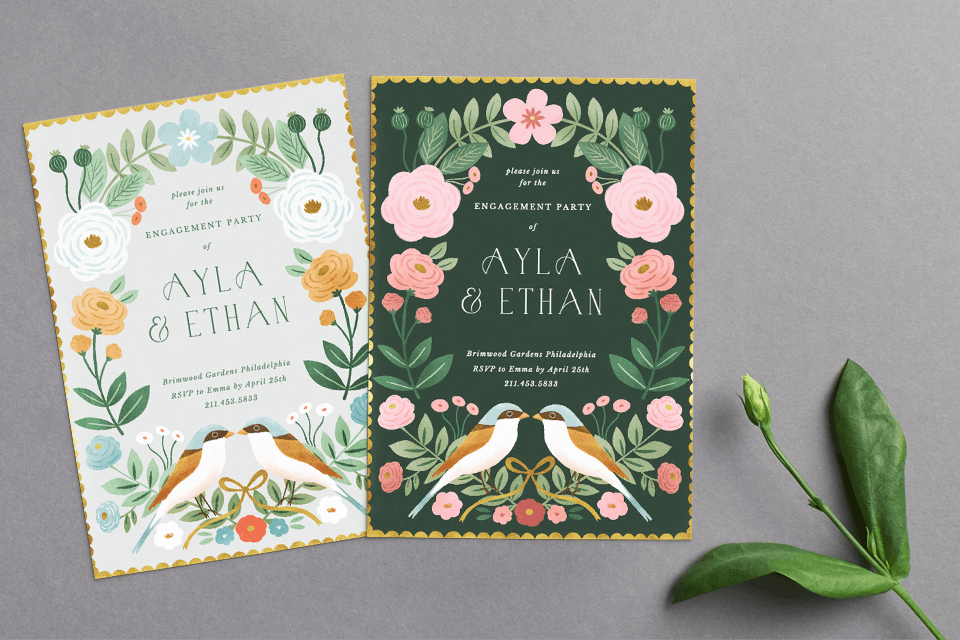 Engagement invitations featuring charming illustrations of lovebirds sharing a tender kiss, surrounded by delicate floral motifs. Each invite boasts a unique color palette while maintaining the same delightful design. Placed elegantly on a surface near a budding flower.