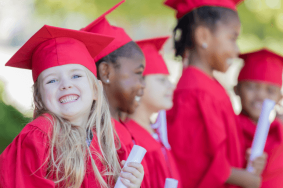 Preschool graduation ceremony: Children donning cheerful red capes and graduation caps, beaming with joy on their special day.