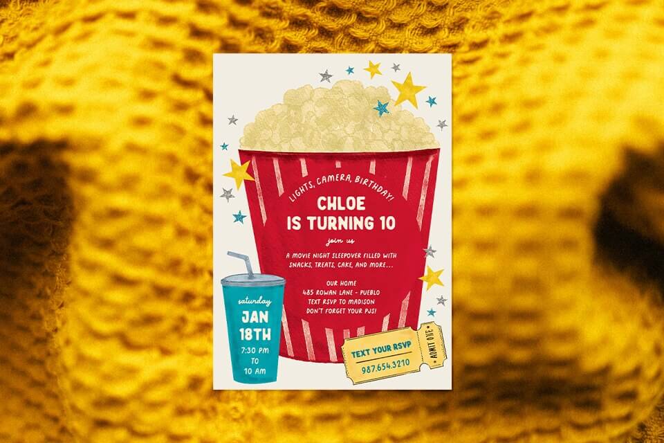 popcorn-movie-birthday-invite-blanket (1) Colorful movie night birthday invitation featuring a giant red popcorn bucket with text announcing Chloe’s 10th birthday, surrounded by stars, a blue soda cup with party details, and a yellow admit-one ticket, placed on a cozy yellow blanket background.