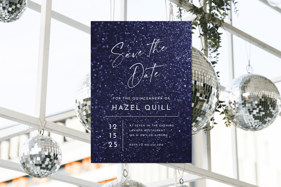 1 save-the-date-quince-birthday-invite-decor Save the date quinceañera card with a deep blue glitter-style background, white script text, and event details, displayed among hanging silver disco balls in a bright indoor setting.