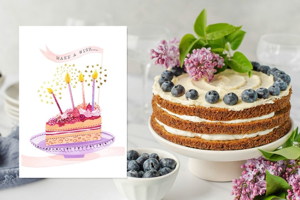 make-a-wish-mother-birthday-card-cake (1) Birthday card beside a layered cream cake topped with blueberries and lilac flowers; the card shows an illustrated slice of cake with lit candles and the words “Make a wish,” styled in soft pastel colors.
