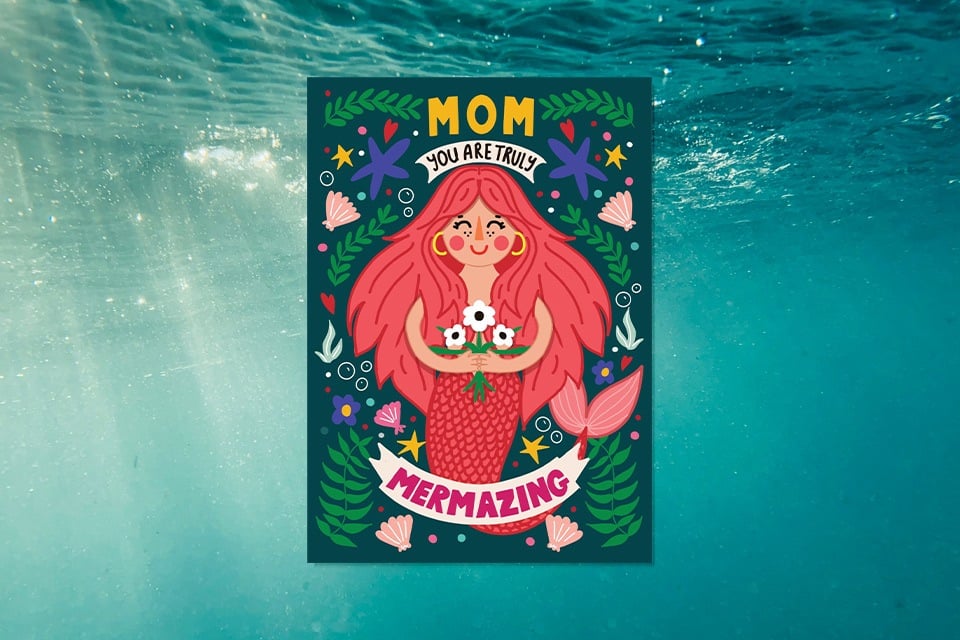 mermazing-mom-birthday-card (1) Playful illustrated birthday card for mom featuring a smiling pink-haired mermaid holding flowers, surrounded by sea plants and stars, with the text “Mom, You Are Truly Mermazing” on a teal underwater background.