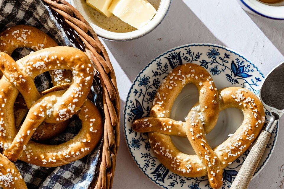 easter pretzels celebration Freshly baked soft pretzels topped with coarse salt served in a basket and on a patterned plate with butter on the side.