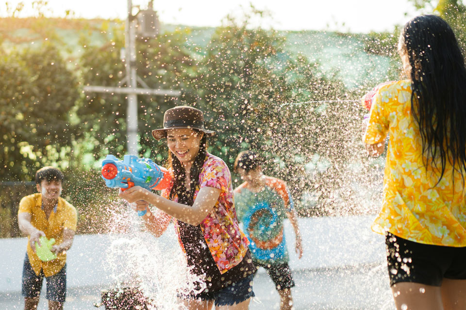 easter-water-games Group of people playing outdoors with water guns, splashing water in bright sunlight during a lively summer water fight.